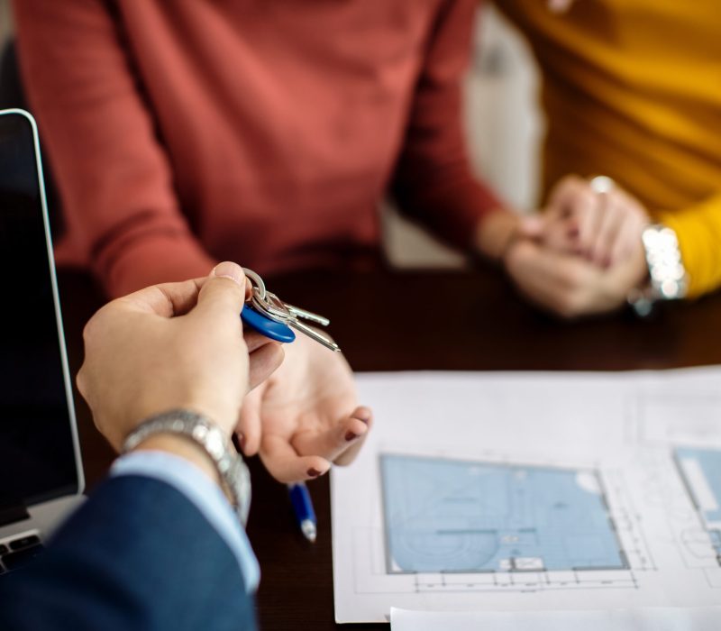 Close-up of a couple receiving keys of their new home on a meeting in the office.